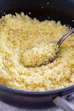 a pan filled with rice and a spoon in it