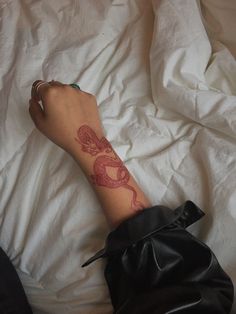 a person's arm with a tattoo on it laying in bed next to a white sheet