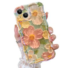 a person holding up a phone case with flowers on it, and the back cover is made out of clear plastic