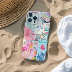 a cell phone case sitting on top of a sandy beach next to a straw hat