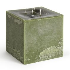 a green square candle holder with two candles in it