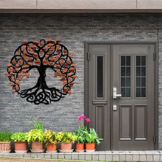 a tree with orange leaves is on the side of a brick building next to potted plants