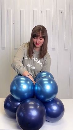 a woman sitting at a table with blue balloons in the shape of an octopus on it