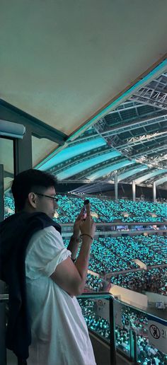 a man taking a photo with his cell phone in front of an audience at a sporting event