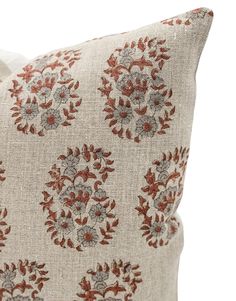 a pillow with red and grey flowers on it's side, sitting on a white surface