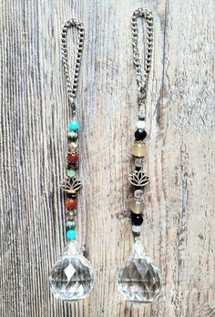 two necklaces with different colored beads and chains on a wooden surface, one is hanging from a chain