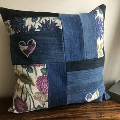 a blue pillow with patchwork and hearts on the front is sitting on a wooden table