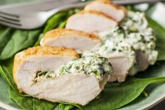 two slices of pork with spinach and cream sauce on a green leafy plate