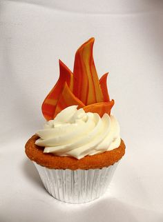 a cupcake with white frosting and an orange flame decoration on it's top