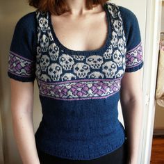 a woman standing in front of a door wearing a sweater with skulls and flowers on it