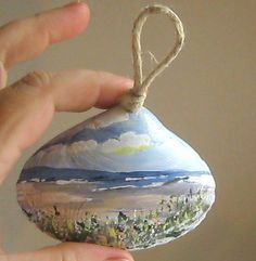 a hand holding an ornament with a painting on it