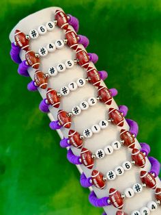 a close up of a beaded bracelet with footballs on it and numbers in the middle