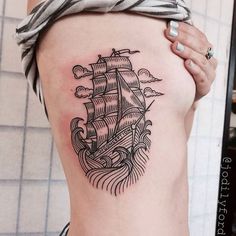 a woman with a tattoo on her stomach has a ship in the ocean and waves