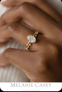 a woman's hand wearing a gold ring with a diamond on it and the words melanie casey fine jewelry