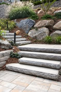 stone steps lead up to the top of a hill with plants and rocks on it