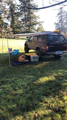 a black suv parked in the grass next to a picnic table and chair under a tent