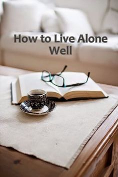 an open book sitting on top of a wooden table next to a cup of coffee