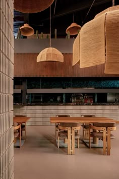 an empty restaurant with wooden tables and hanging lights above it's counter top area