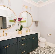 a bathroom with two round mirrors above the sinks and a toilet in front of it