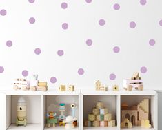 the shelves are filled with wooden toys and wall decals in purple polka dot pattern