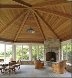 a large covered patio with wicker chairs and tables in front of an open fire place