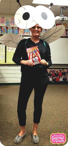 a woman standing in front of a book display wearing a paper hat with eyes and nose