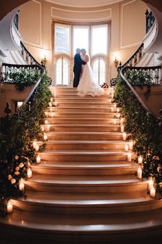 a bride and groom are standing on the stairs in front of candles at their wedding