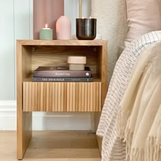 a nightstand with books and candles on it