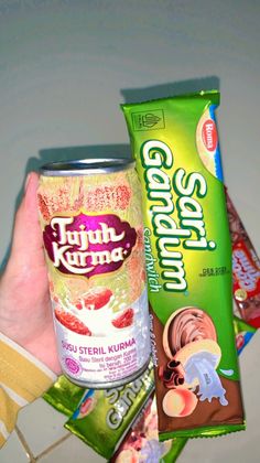 a hand holding a can of gummy and some other candy bar items next to each other