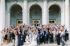 a large group of people posing for a photo in front of a building with columns