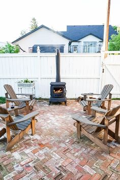 three wooden chairs sitting on top of a brick patio next to a wood burning stove