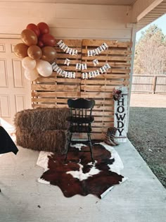 a cowhide rug and chair in front of a wooden wall with balloons on it