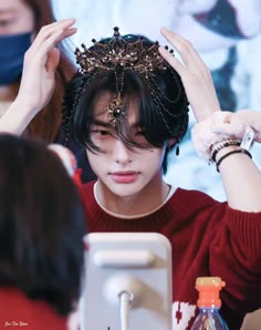 a young man with a crown on his head at a table in front of a computer