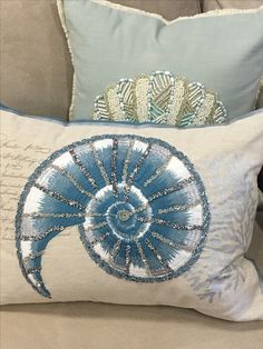 a decorative pillow on a couch next to a blue and white pillow with an intricate design