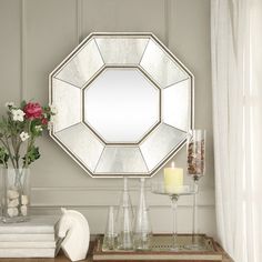 a mirror sitting on top of a table next to a vase with flowers in it