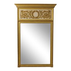 a gold framed mirror with an ornate design on the top and bottom edge, against a white background