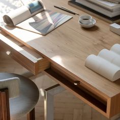 a wooden desk topped with lots of books and papers next to a cup of coffee