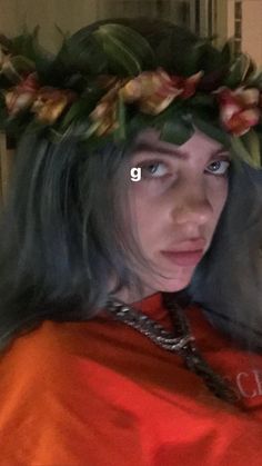 a woman with long hair wearing a flower crown on her head and looking at the camera