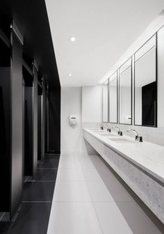 a long bathroom with two sinks and mirrors on the wall next to urinals