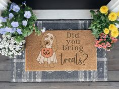 a door mat that says did you bring treats? with a dog holding a pumpkin