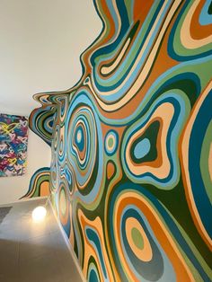 an abstract painting on the wall next to a hallway with lights and paintings behind it