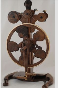 a wooden spinning wheel with two children on it's sides and the wheels are made out of wood