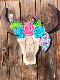 a cow skull with flowers on it is hanging on a wooden fence post in front of a building