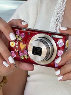 a woman holding a red camera in her hands with flowers painted on the front and sides