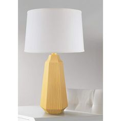 a yellow table lamp sitting on top of a white table