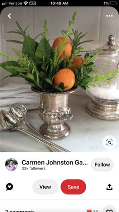 a silver vase filled with oranges on top of a table