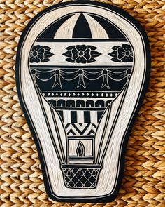 a hot air balloon painted on the side of a woven basket with black and white designs