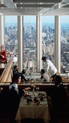 people sitting at tables in a restaurant overlooking the city