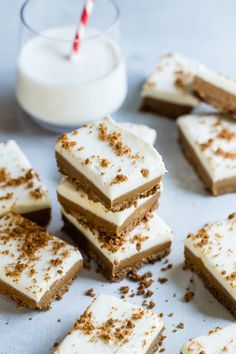 several pieces of cake with white frosting and sprinkles next to a glass of milk