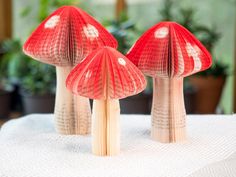 three red mushrooms sitting on top of a white table